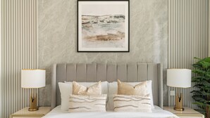 A bedroom with a bed, two bedside lamps, a framed artwork on the wall, and a potted plant. - Silkhaus The Grand (Dubai)