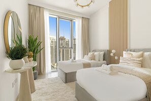 A modern hotel room with a large bed, a smaller bed, a sitting area, a large mirror, and a view of the cityscape. - Silkhaus The Grand (Dubai)