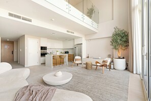 A modern living room with a sofa, a coffee table, and a dining area with chairs and a table. - Silkhaus Azure (Abu Dhabi)