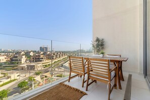 A balcony with a view of a cityscape, wooden furniture, and a potted plant. - Silkhaus Azure (Abu Dhabi)