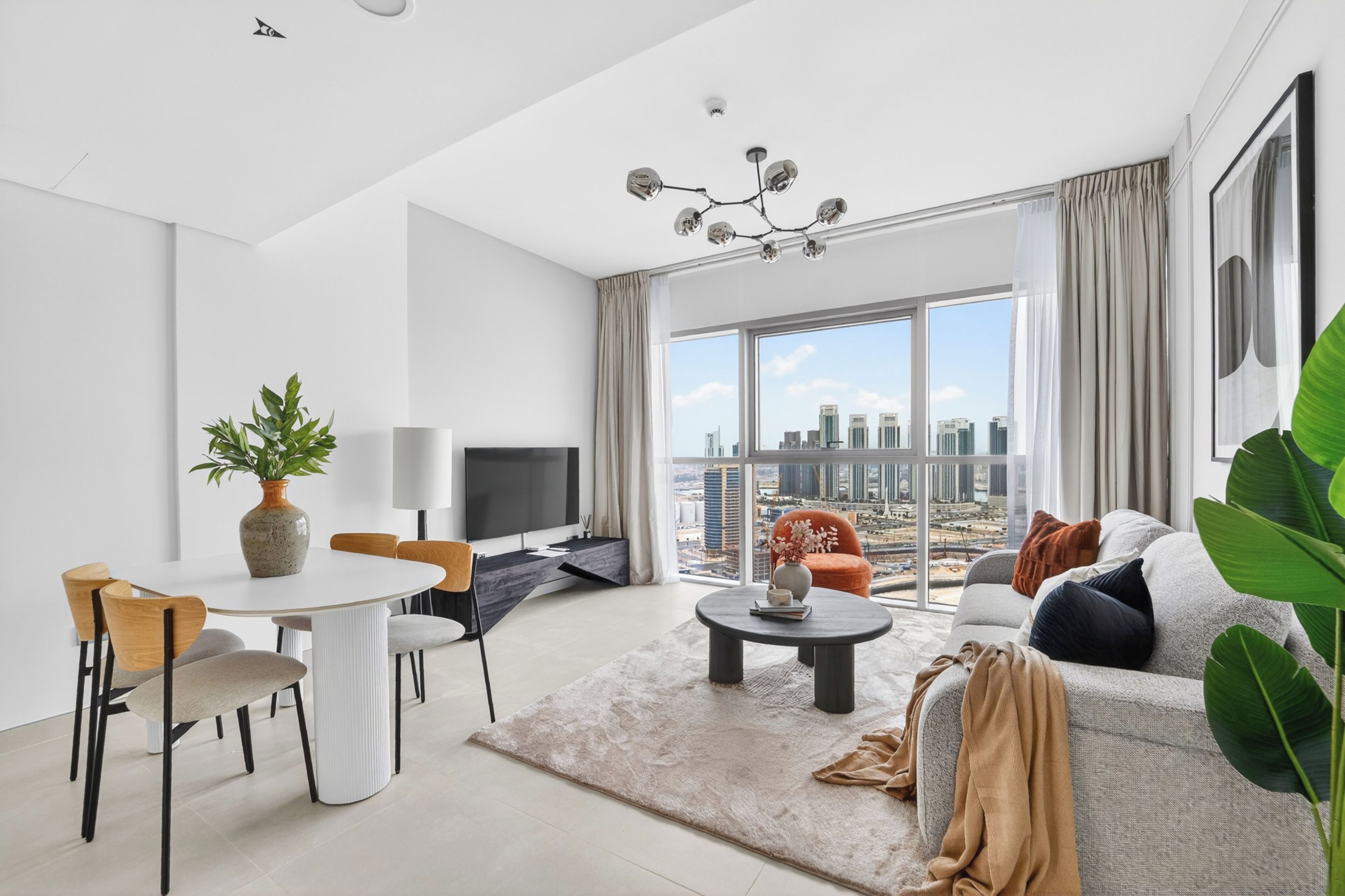 Ein modernes Wohnzimmer mit Stadtblick, ein Essbereich mit Stühlen und einem Tisch sowie ein großes Fenster mit Vorhängen.