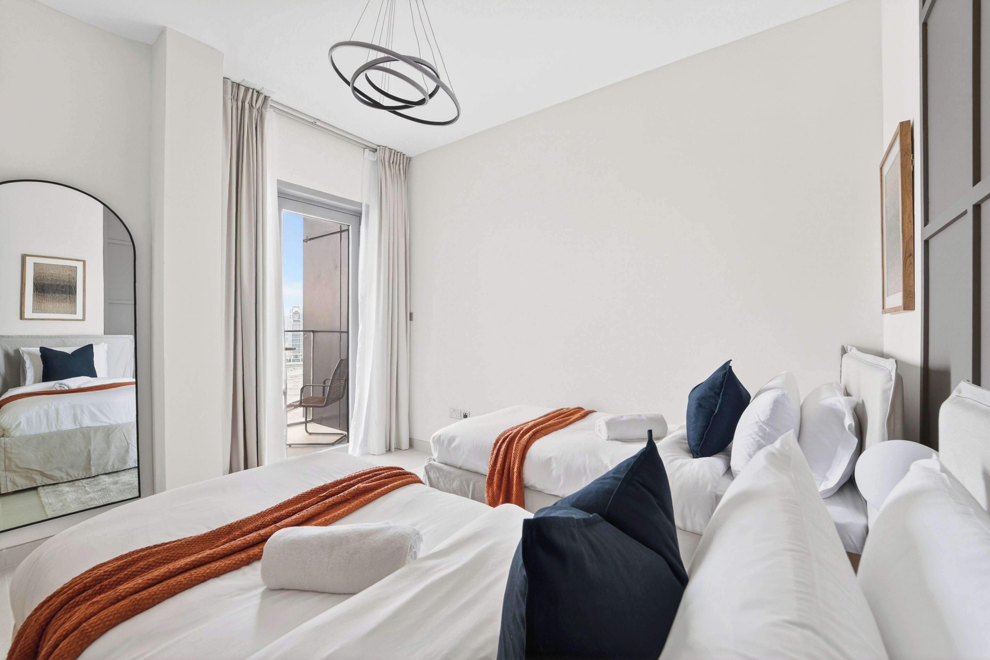 A hotel room with two beds, a large mirror, and a view of the outside.