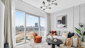 Un salon moderne avec une grande fenêtre, un canapé, une table basse et un fauteuil.
