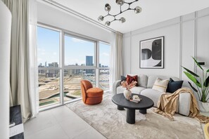 Ein modernes Wohnzimmer mit großem Fenster, einer Couch, einem Couchtisch und einem Sessel.