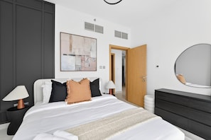 Ein modernes Schlafzimmer mit einem großen Bett, Nachttischlampen, einer Kommode und einem Spiegel.