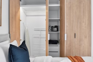 Quarto com cama, travesseiros, mesa de cabeceira, guarda-roupa e um varal.