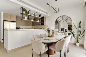 Een moderne keuken met inbouwapparatuur, een eethoek met een marmeren tafel en een grote potplant.
