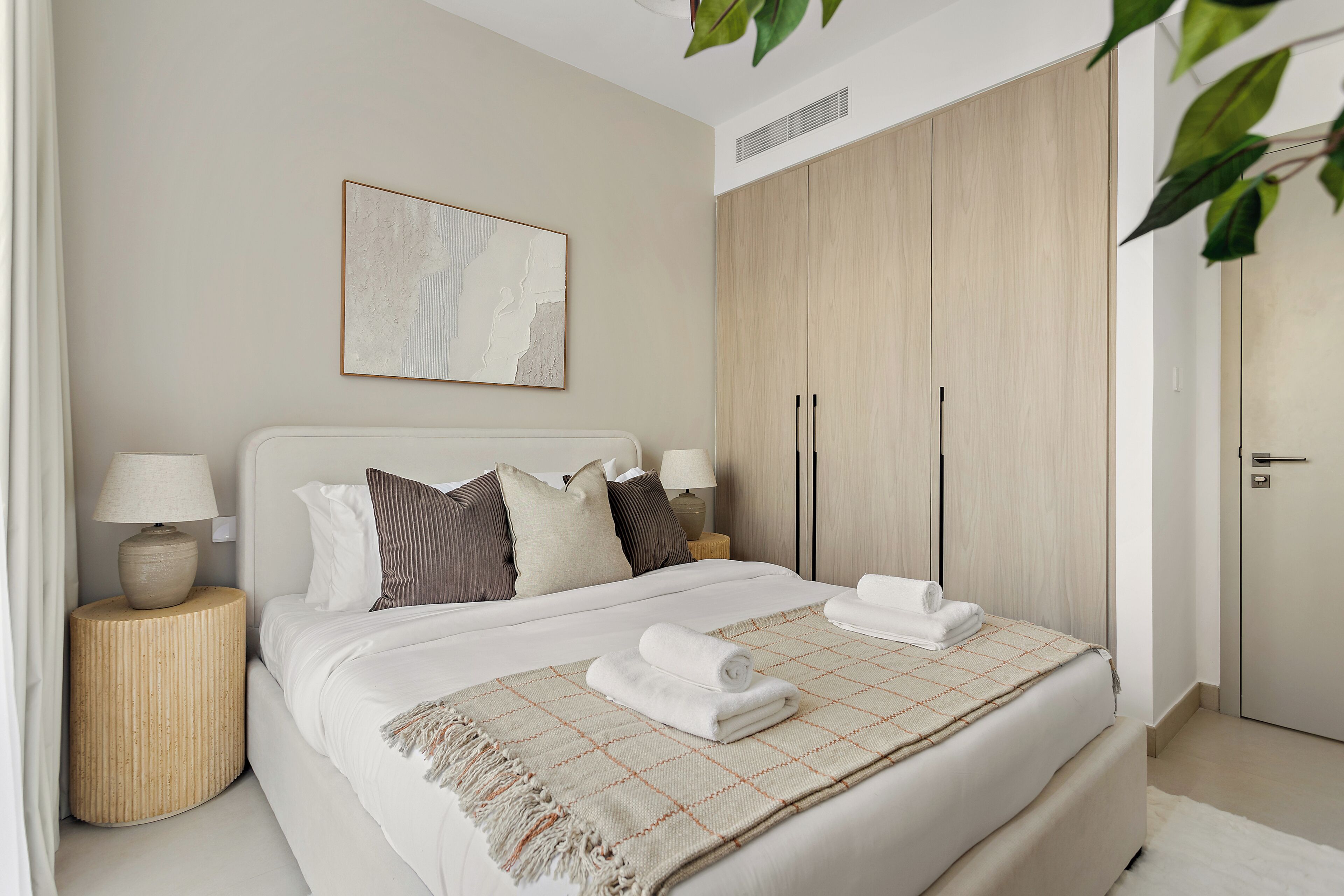 Une chambre d’hôtel avec un lit, des lampes de chevet, une grande œuvre d’art au mur et une armoire.