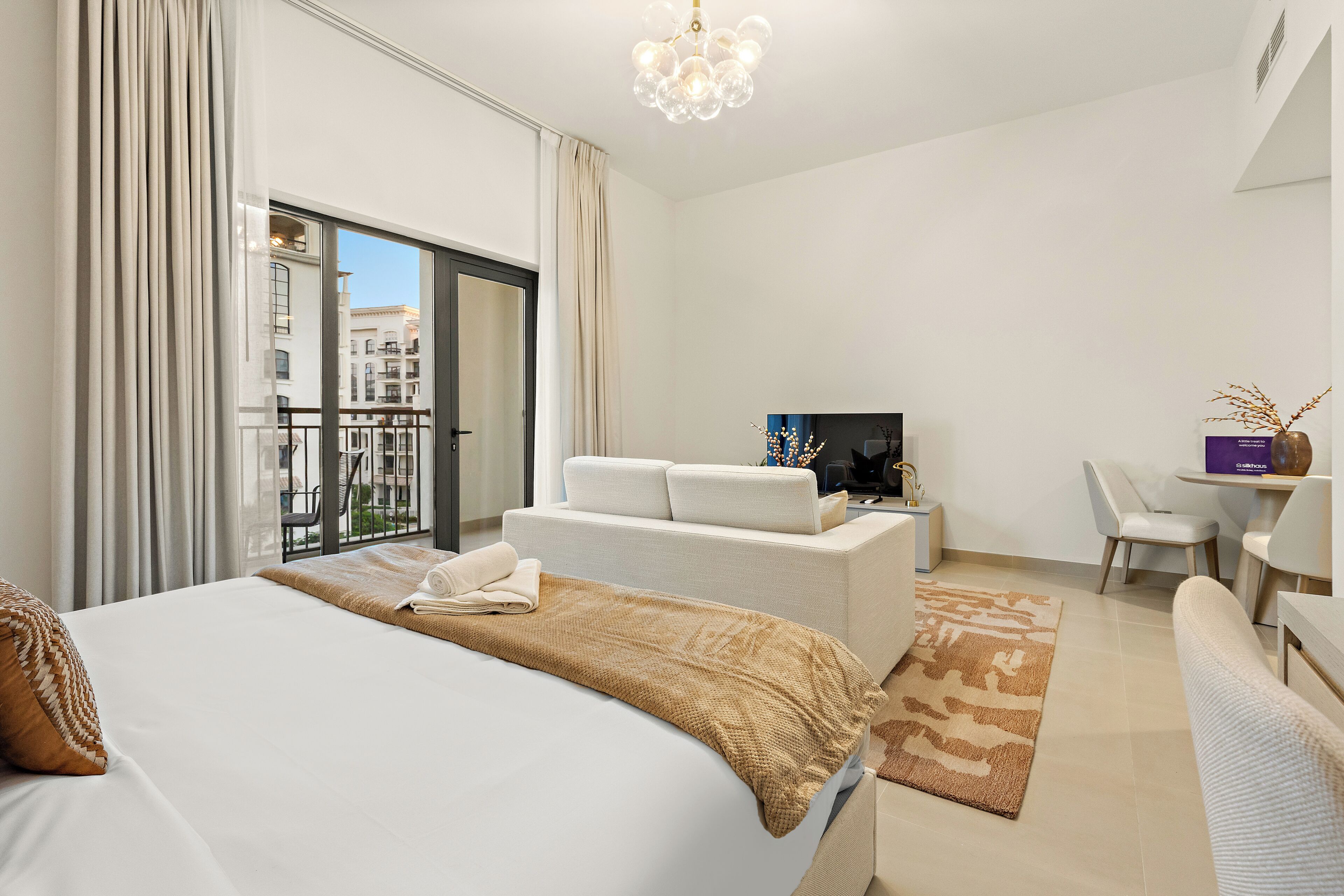 Ein modernes Hotelzimmer mit einem großen Bett, einer Couch, einem Schreibtisch und einem Fernseher.