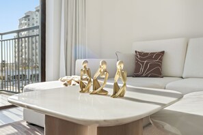 A modern living room with a white sofa, a coffee table, and decorative golden figures. - Silkhaus Al Battros (Abu Dhabi)