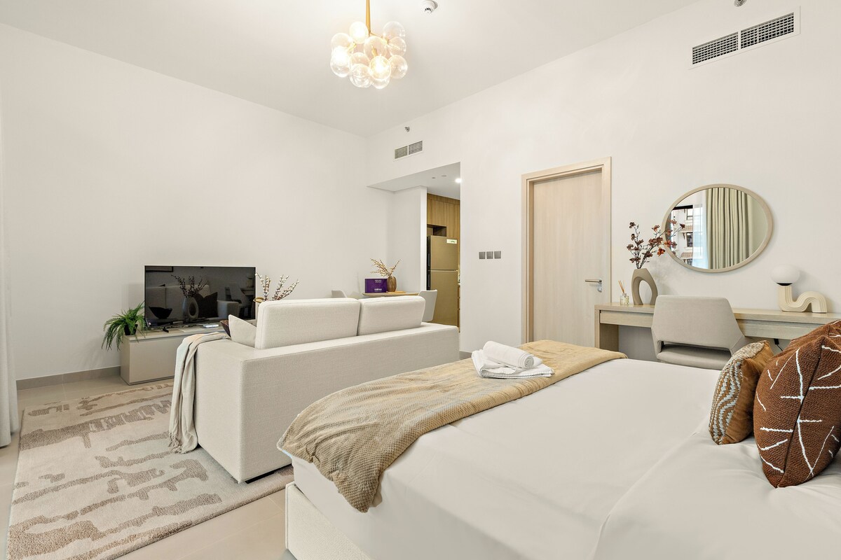 Una habitación de hotel moderna con cama, sofá, escritorio, televisor y espejo.