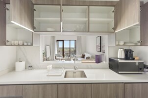 Una cocina moderna con lavavajillas incorporado, cafetera y vistas a la ciudad a través de amplios ventanales.