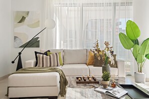 A modern living room with a sofa, a coffee table, and a large window with sheer curtains. - Silkhaus Myrtle 1 (Dubai)