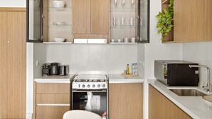 Una cocina moderna con armarios de madera, horno empotrado y una encimera con tostadora y hervidor.