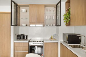 Eine moderne Küche mit Holzausstattung, einem eingebauten Backofen und einer Arbeitsplatte mit Toaster und Wasserkocher.