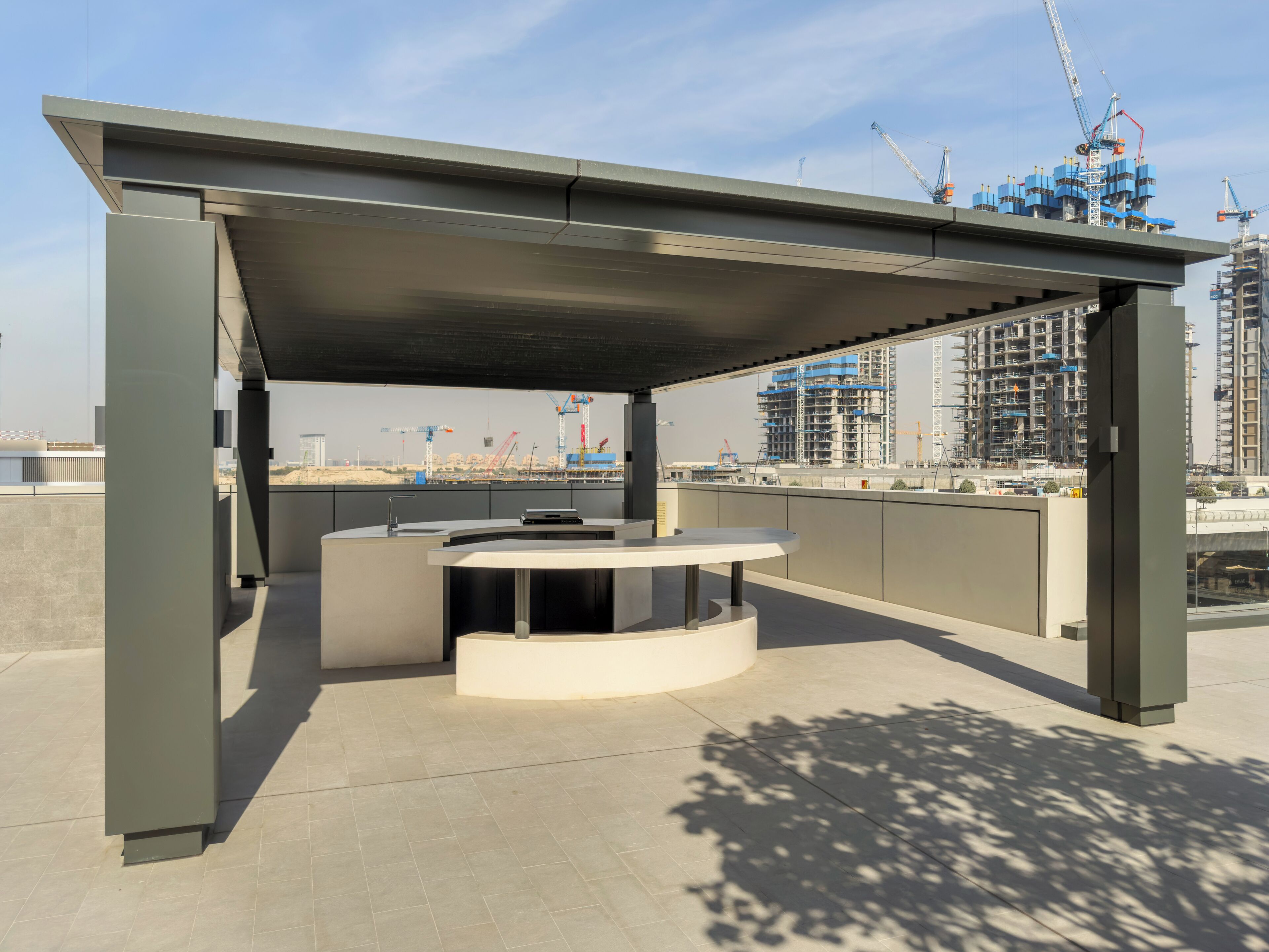 An outdoor seating area with a table and chairs, a covered section, and a view of a construction site in the background.