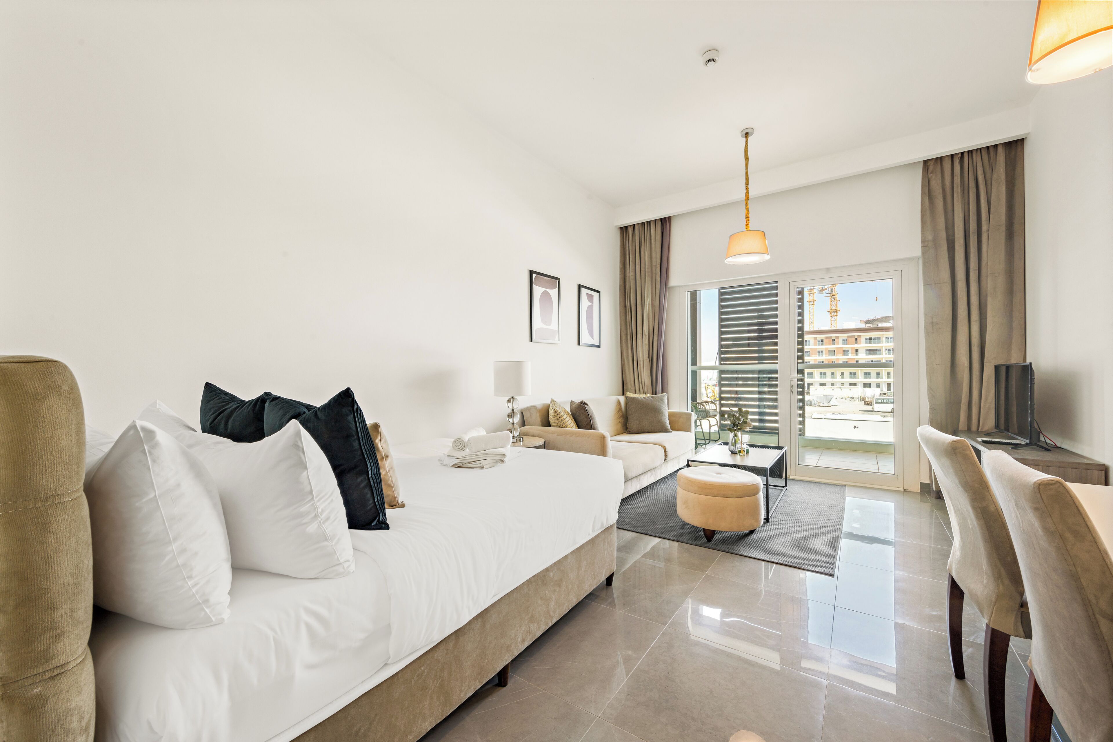 A hotel room with a large bed, a sofa, a coffee table, and a TV.