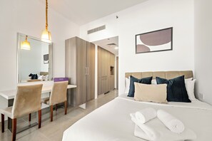 Ein Hotelzimmer mit einem Bett, einem Schreibtisch, einem Sessel, einem Spiegel und einem gerahmten Kunstwerk an der Wand.