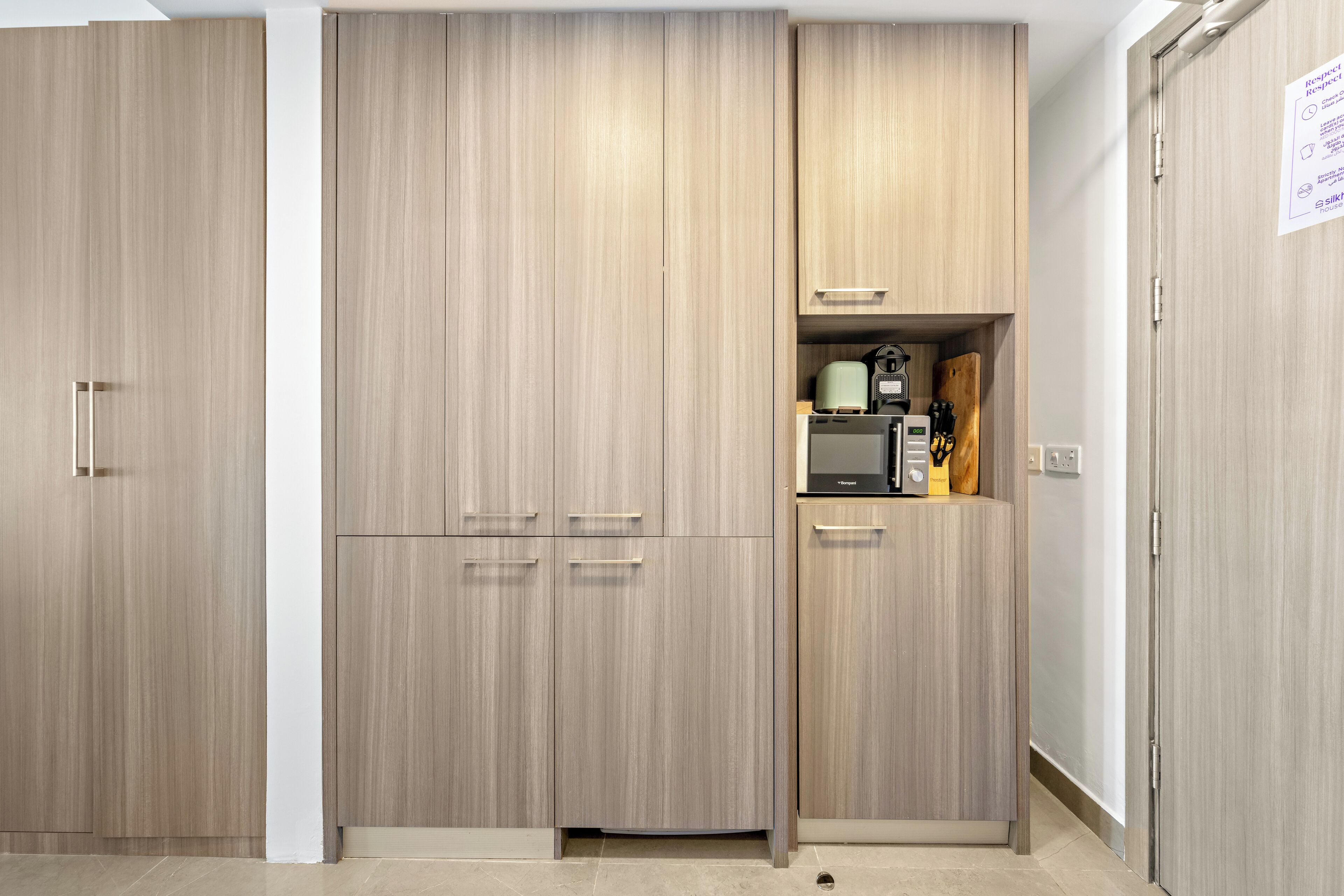Ein Zimmer mit Kleiderschrank, Küchenzeile und einer Tür mit einer Durchschlag.