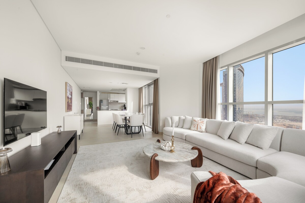 Ein modernes Wohnzimmer mit Fernseher, Essbereich und einer Couch mit Blick auf die Stadt.