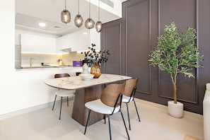 A modern kitchen with white cabinetry, a marble countertop, and pendant lighting. - Silkhaus Radiant Heights (Abu Dhabi)