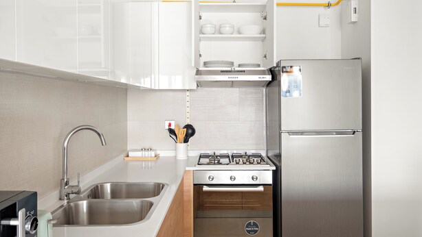 Une cuisine moderne équipée d’appareils électroménagers en acier inoxydable, d’une cuisinière à gaz et d’un four encastré.