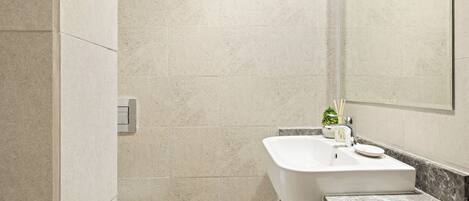 A modern bathroom with a white sink, a mirror, and a marble countertop.