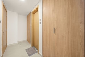 A hallway with wooden doors, a light-colored floor, and a small rug. - Silkhaus Radiant Heights (Abu Dhabi)
