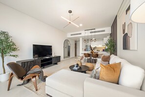 Ein modernes Wohnzimmer mit Flachbildfernseher, einer Couch, einem Couchtisch und einem Essbereich mit Stühlen und Tisch.