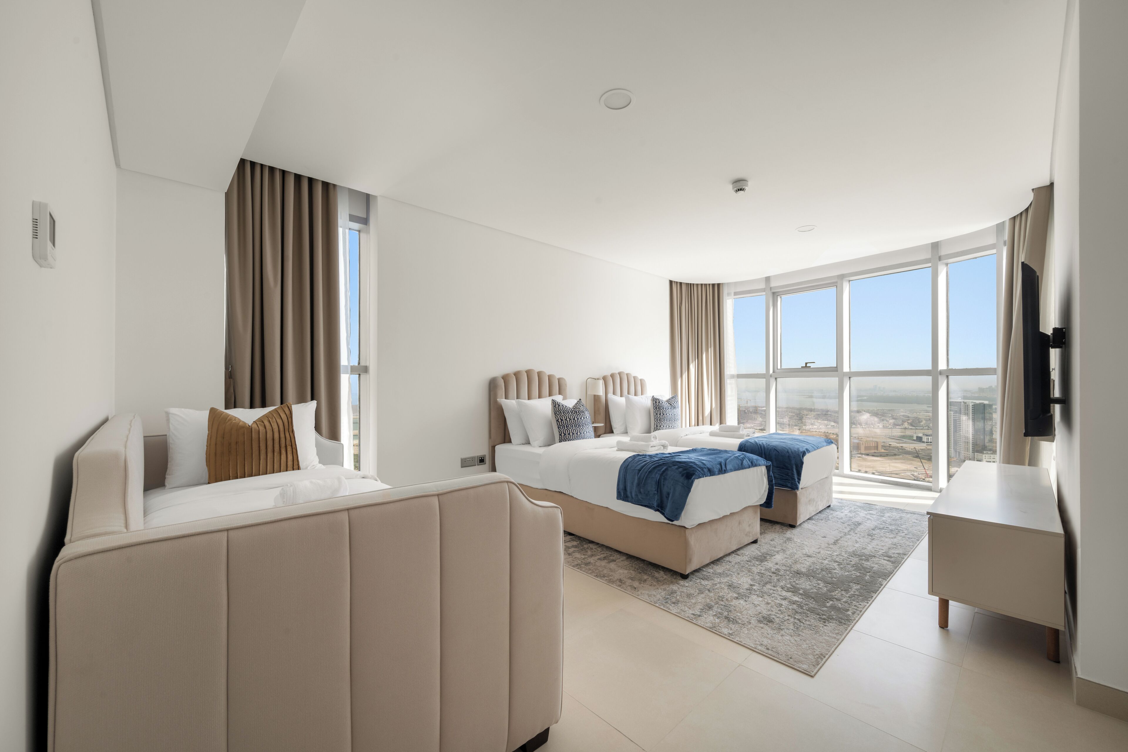 A modern hotel room with a large bed, a sofa, and a desk.