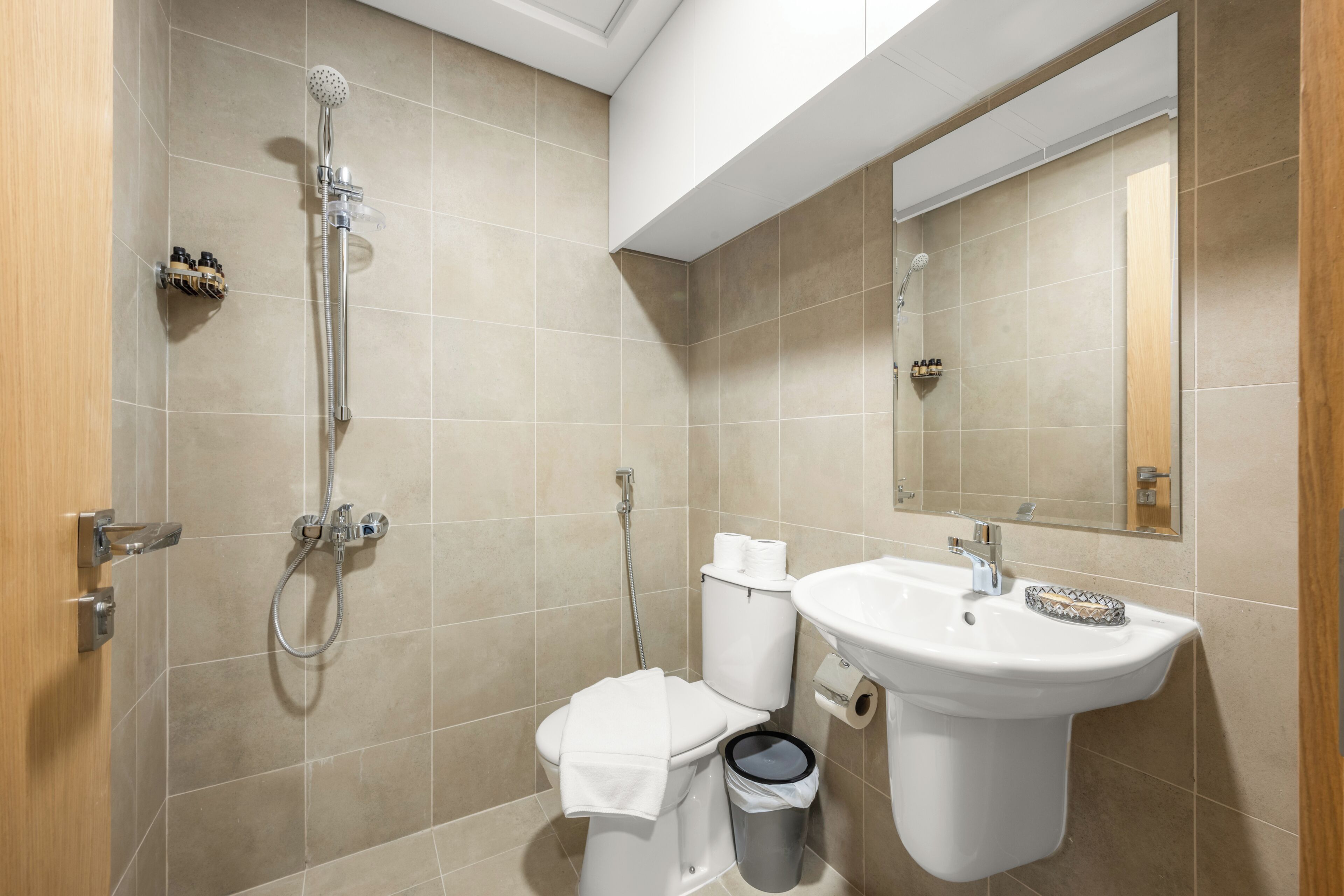 A bathroom with a shower, toilet, sink, and mirror.
