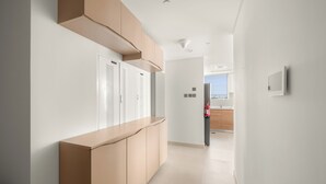 Un couloir moderne avec un banc intégré, un extincteur et une vue sur un espace cuisine.