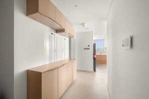 Ein moderner Flur mit integriertem Sitzplatz, einem Feuerlöscher und Blick in einen Küchenbereich.