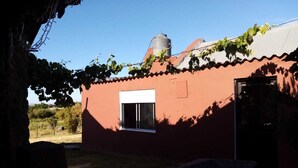 Ein rotes Gebäude mit einem weißen Fenster und einer Tür, umgeben von einem Garten und einem Baum.