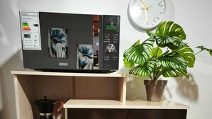 Een keuken met een koffiezetapparaat, een klok en een plant in een pot op het aanrecht.