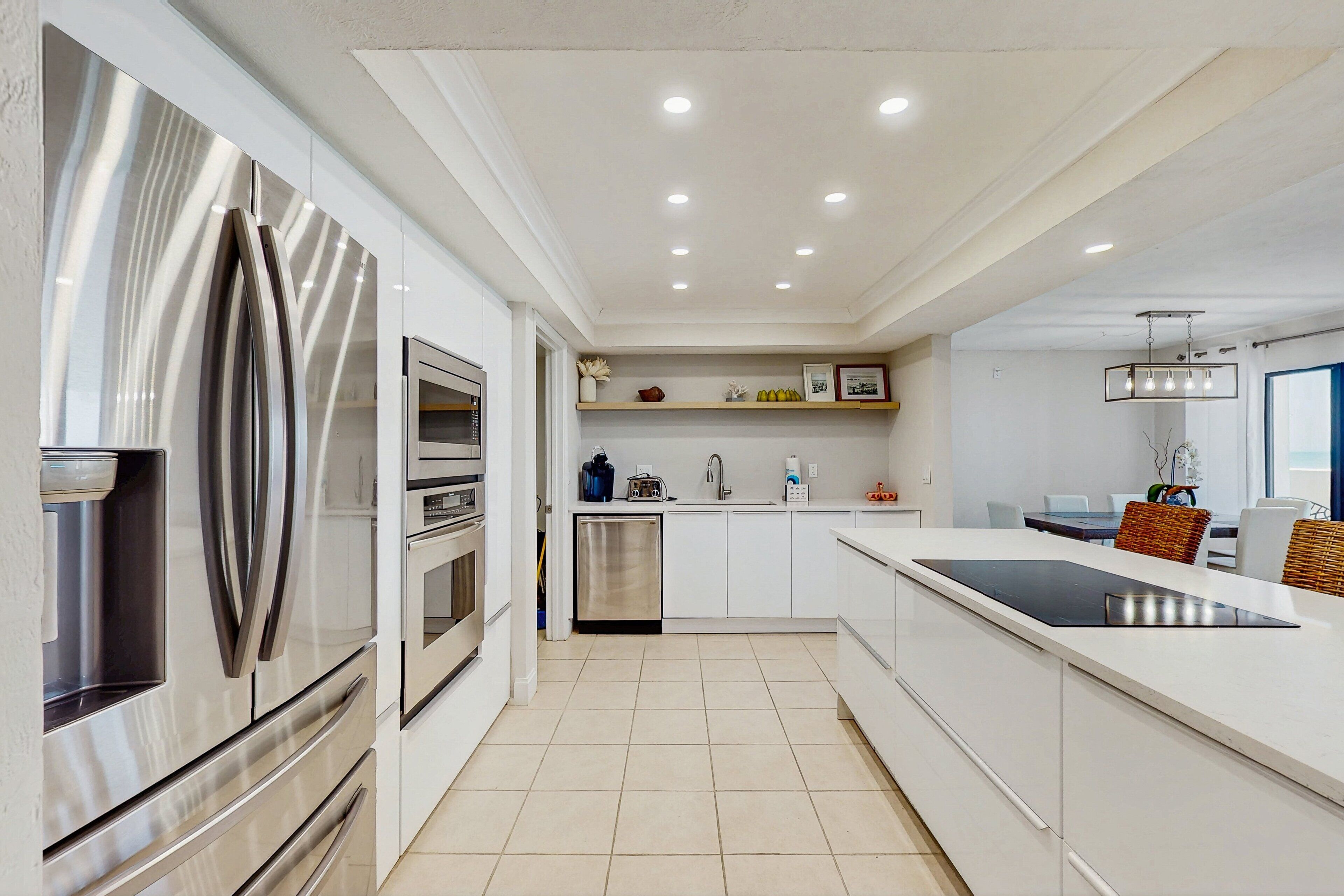 A modern kitchen with stainless steel appliances, white cabinetry, and a central island.