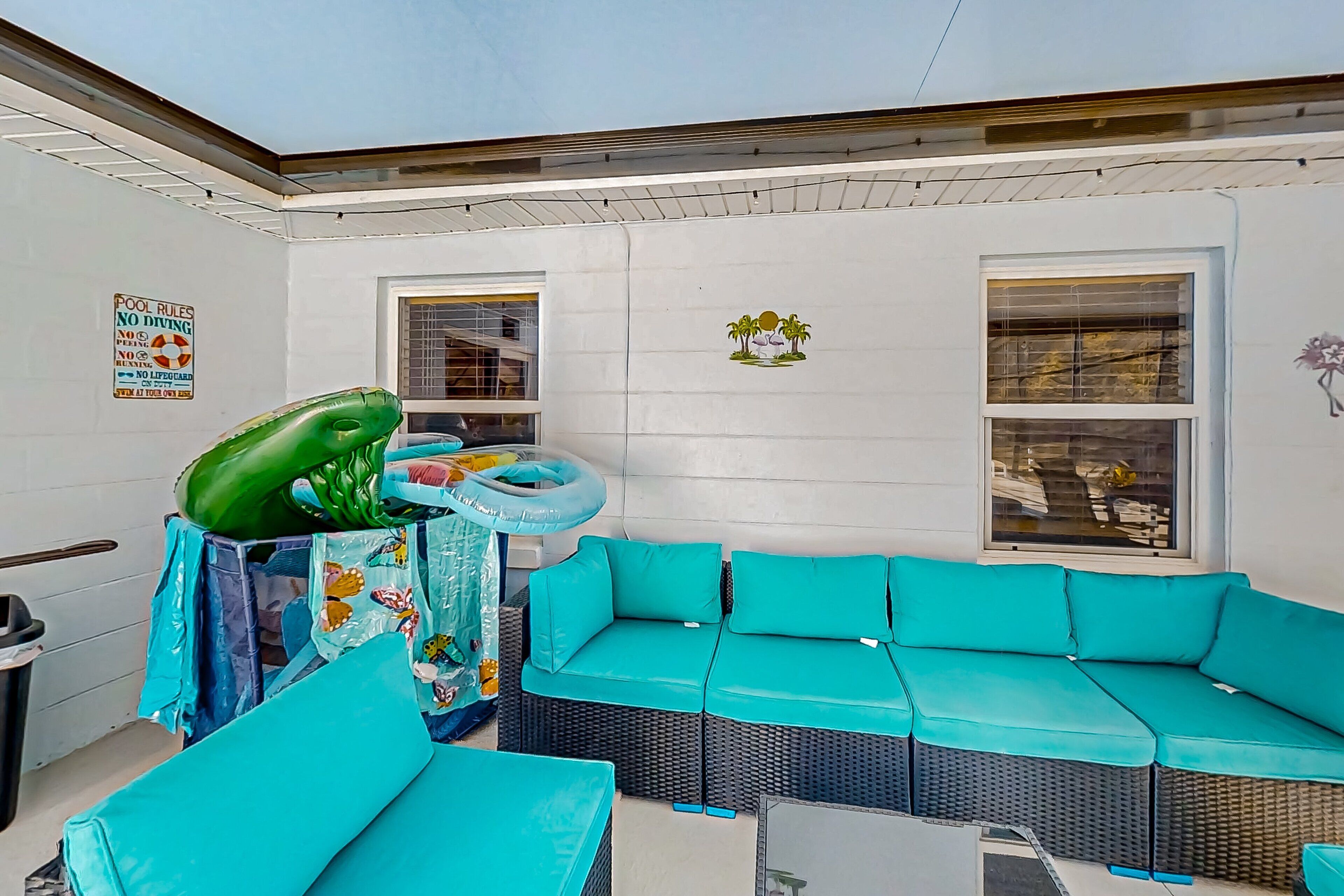 A poolside area with a blue sofa, inflatable rings, and a green inflatable pool.