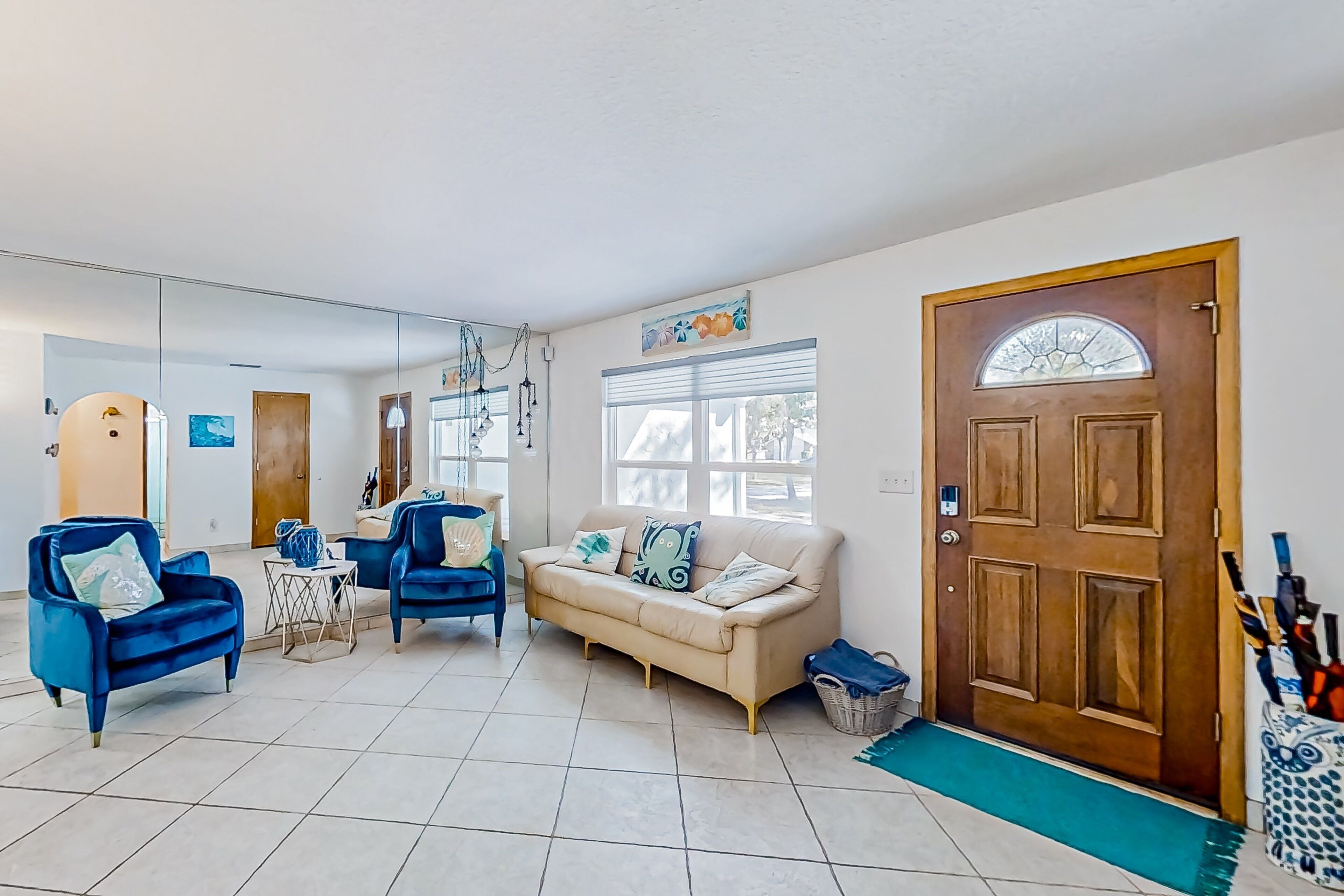 A living room with a beige sofa, blue armchairs, and a wooden door with a window.
