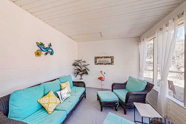 A cozy room with a sofa, chairs, a small table, and a decorative flamingo. - Port Orange Linda's Lizard Landing (Port Orange)
