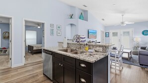 A modern kitchen with dark cabinets, a granite countertop, and a double sink. - Terrapin Station (Ormond Beach)