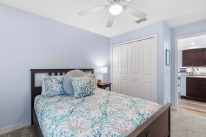 A bedroom with a bed, nightstand, and a ceiling fan. - Terrapin Station (Ormond Beach)
