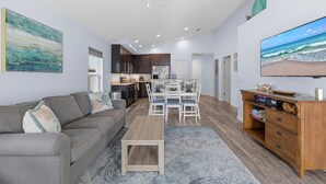 A modern living room with a gray sofa, a coffee table, and a wooden TV stand. - Terrapin Station (Ormond Beach)
