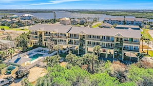 Un hotel de varios pisos con piscina, rodeado de exuberante vegetación y vistas a un lago.