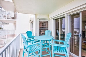 A balcony with a table and chairs, a sliding glass door, and a white railing. - Seawinds 204 - Sea Wind Enjoyment (Ormond Beach)
