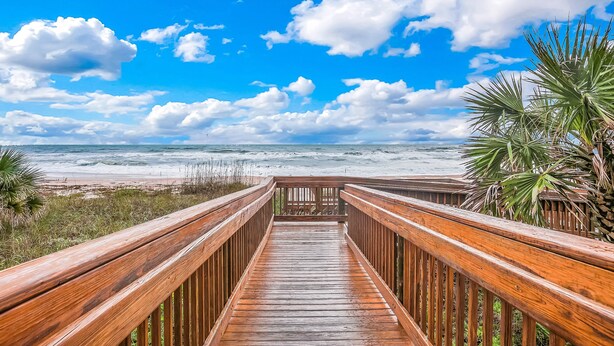 A wooden boardwalk leading to a beach with a clear sky and clouds. - Seawinds 204 - Sea Wind Enjoyment (Ormond Beach)