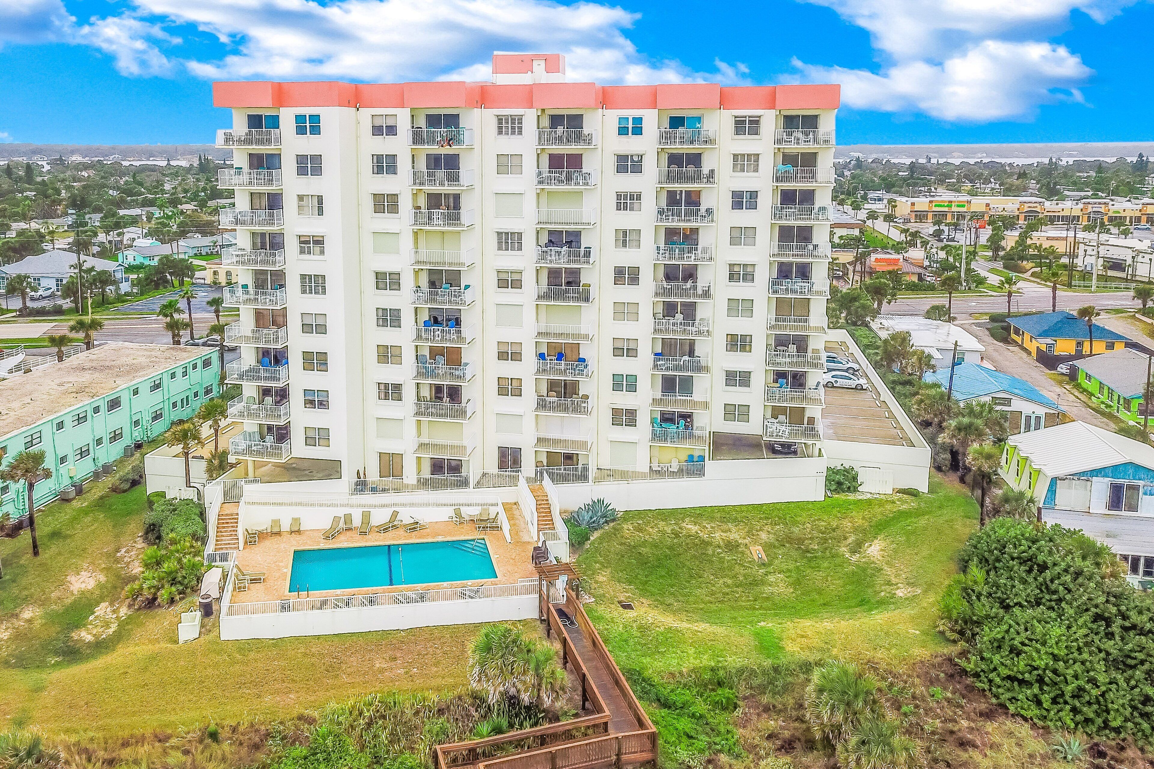 A multi-story hotel with a swimming pool, balconies, and a view of the surrounding area.