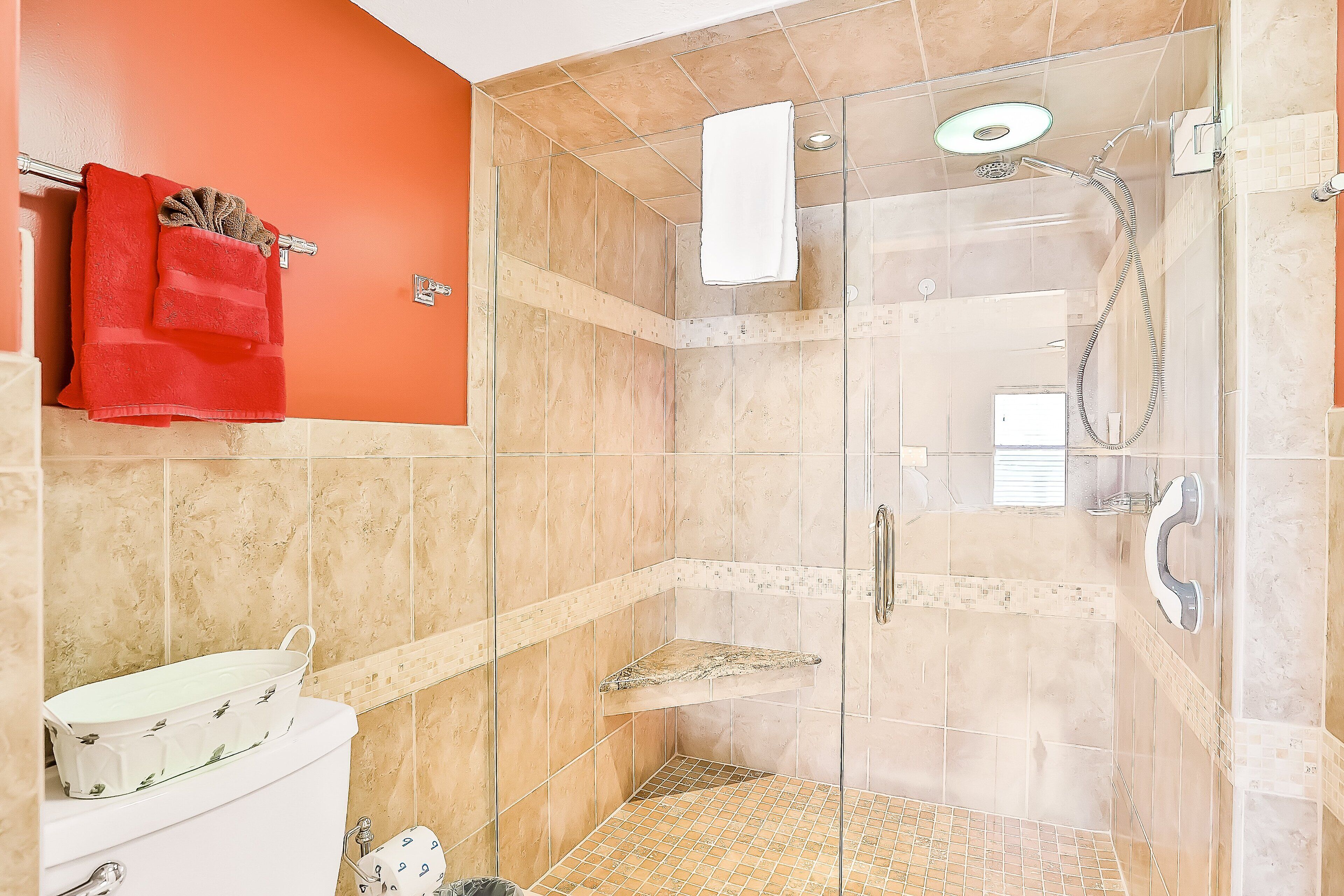 Ducha con cerramiento de vidrio, cabezal de ducha manual y grifo de mano.