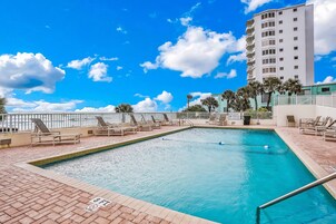 A swimming pool with lounge chairs and a high-rise building in the background.