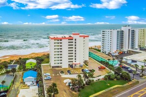 A coastal hotel with multiple high-rise buildings, a parking area, and a view of the ocean. - Seawinds 204 - Sea Wind Enjoyment (Ormond Beach)