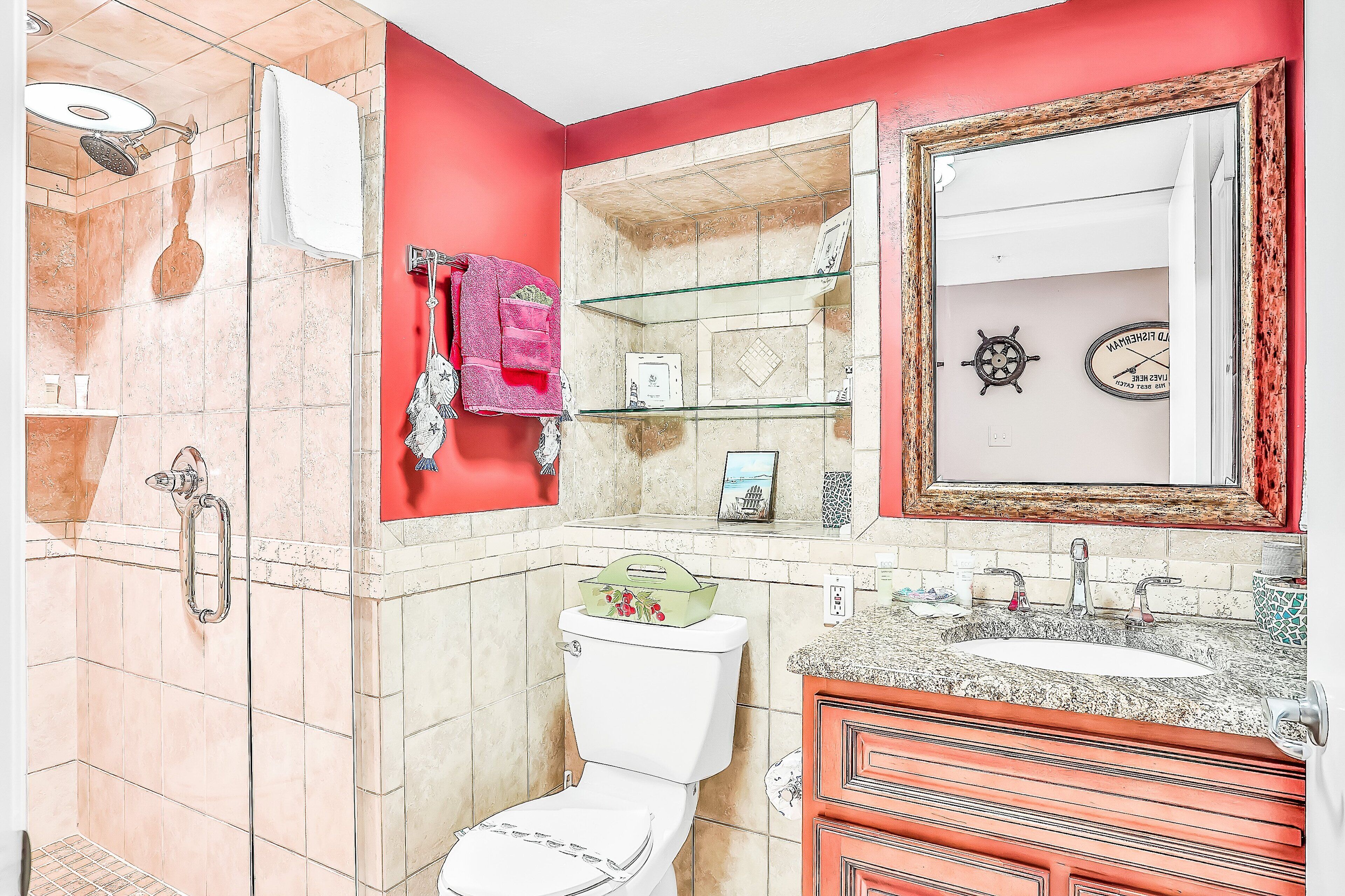 A bathroom with a shower, toilet, sink, and a mirror.